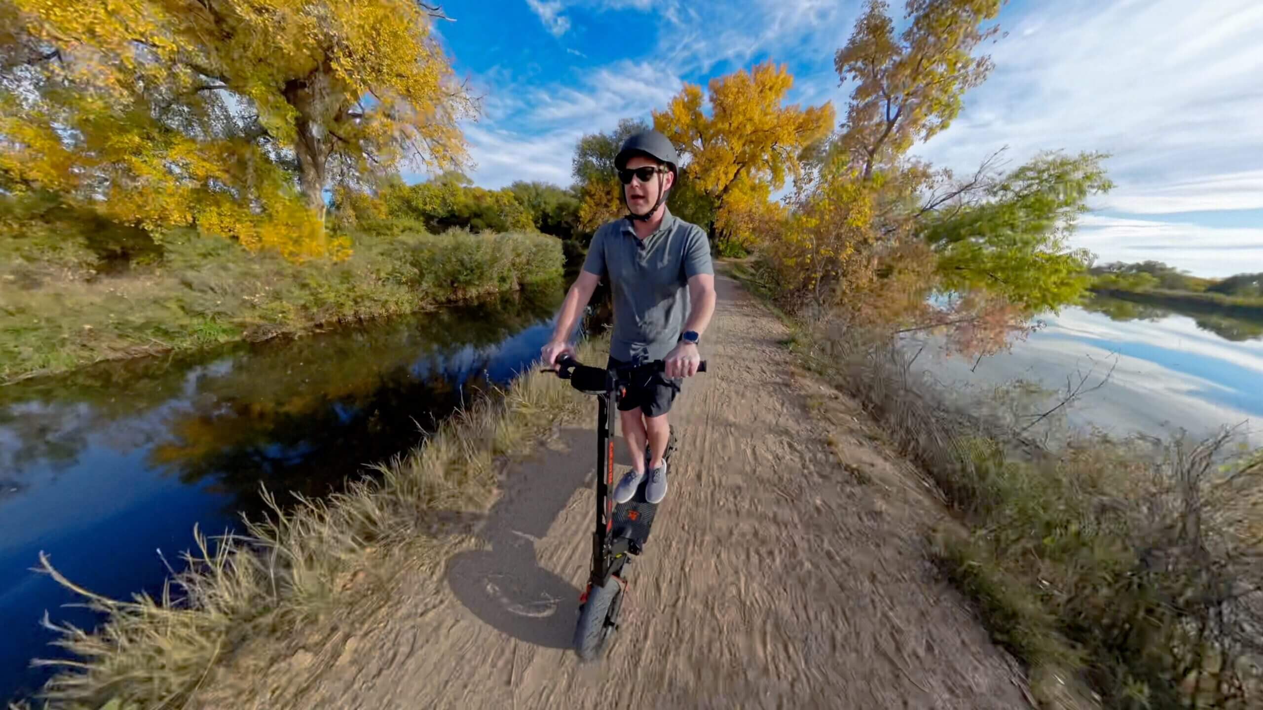 Person riding scooter by waterway.