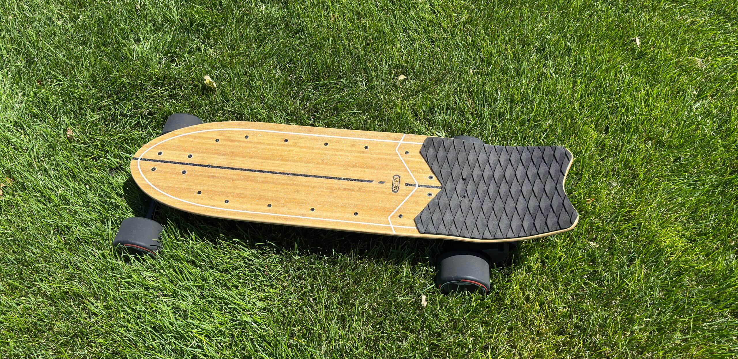 Wooden skateboard on green grass